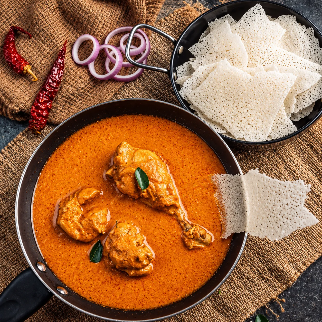 Authentic Karnataka Naati Kori village chicken curry in clay vessel with Kori Rotti on banana leaf
